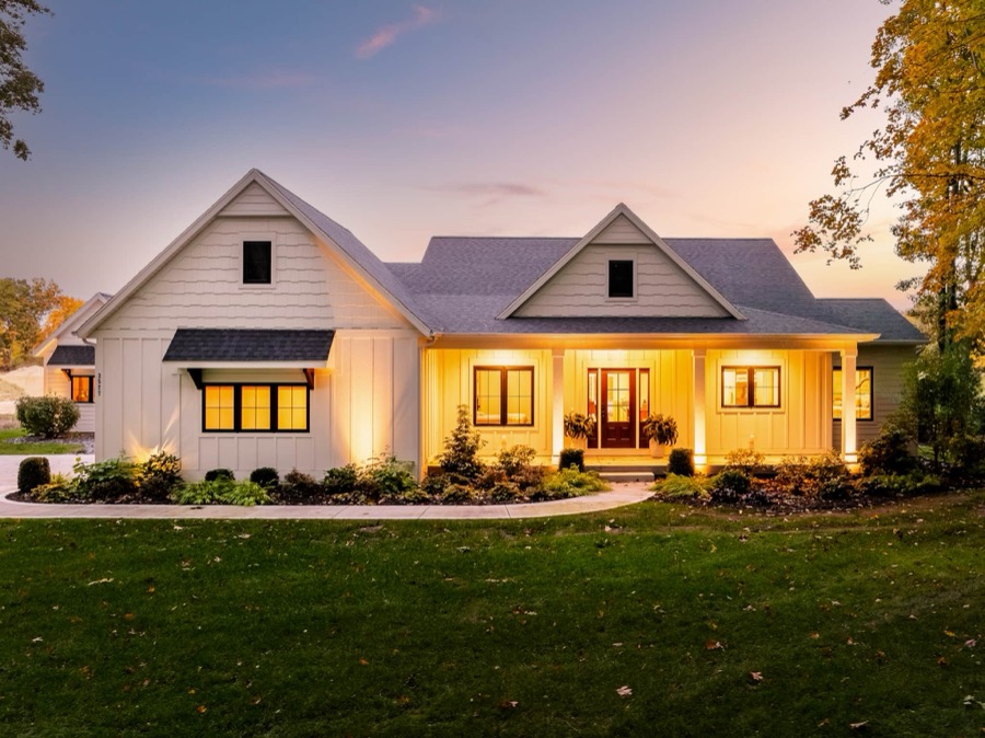 Swimming in Luxury's modern farmhouse exterior at twilight, warm light spilling from every window onto manicured landscaping