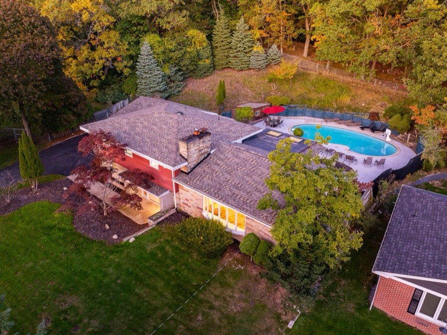 Aerial view of a Norton Shores home with backyard pool ringed by autumn woods